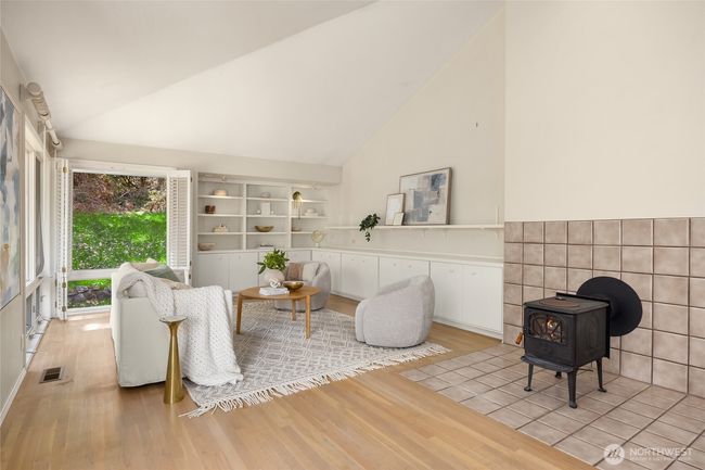 This view showcases the floor to ceiling windows and wood burning stove fireplace. | Image 7