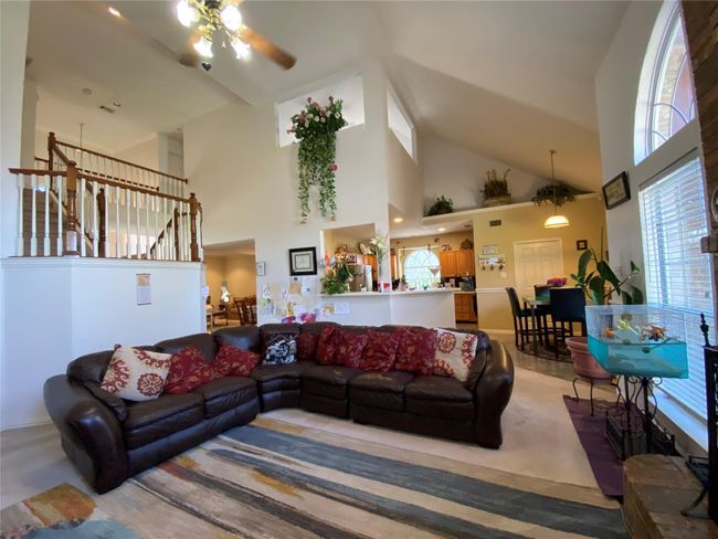 Carpeted living room with a towering ceiling, plenty of natural light, and ceiling fan | Image 10