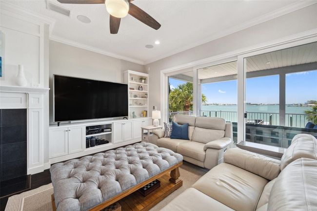 This living room not only features a dreamy water view, but also custom wood cabinetry, built-ins, and a wood burning fireplace surrounded by black granite and a custom mantel. | Image 25