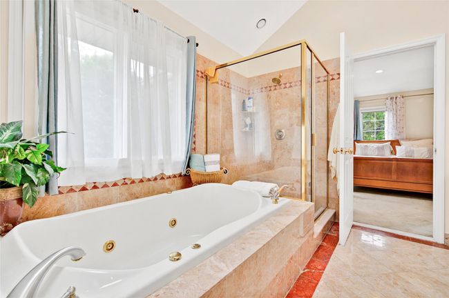 Bathroom featuring ensuite bathroom, a shower stall, a jetted tub, lofted ceiling, and a baseboard radiator | Image 31