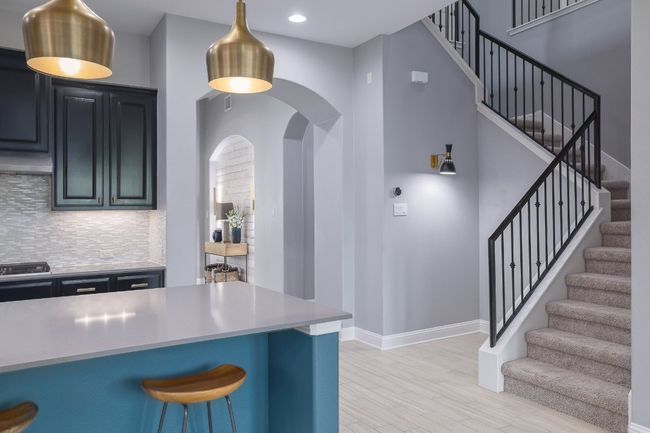 Kitchen featuring arched walkways, backsplash, a kitchen breakfast bar, baseboards, and light wood-type flooring | Image 7