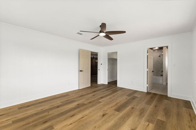 Elegant primary bedroom featuring spacious layout, sleek ceiling fan, and direct access to a modern en-suite bathroom. | Image 20
