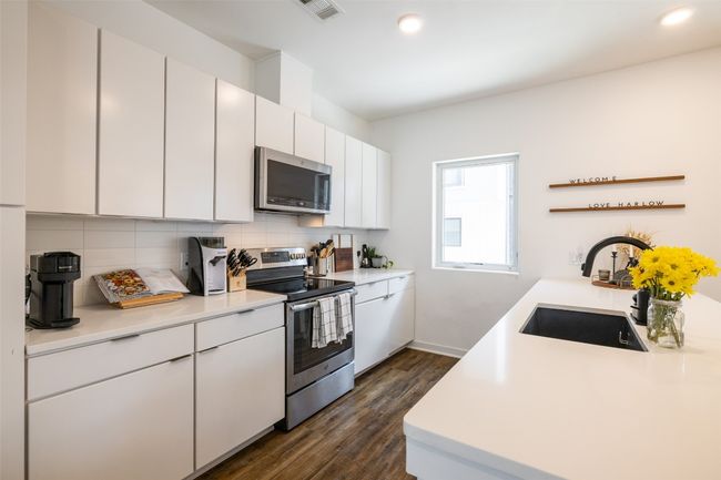 Kitchen featuring tasteful backsplash, visible vents, a sink, dark wood-style flooring, and appliances with stainless steel finishes | Image 9