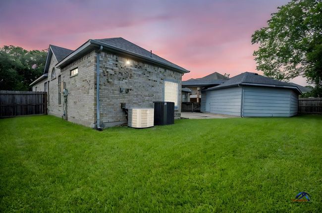 This photo features a backyard with well-maintained grass, a brick exterior, and a detached 3 car garage. The area is fenced, offering privacy. | Image 41