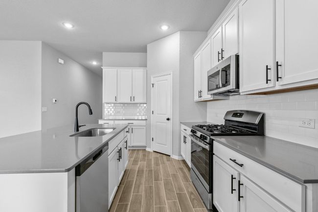 Kitchen featuring an island with sink, tasteful backsplash, recessed lighting, a sink, and stainless steel appliances | Image 10