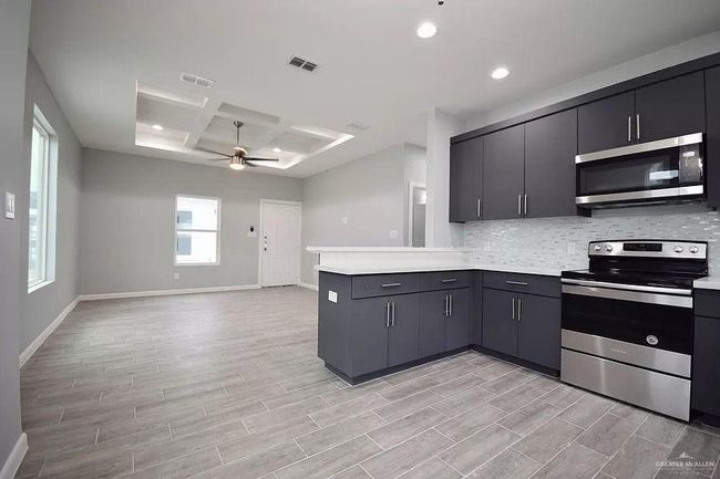 Kitchen with ceiling fan, coffered ceiling, a peninsula, appliances with stainless steel finishes, and visible vents | Image 4