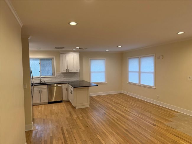 Kitchen featuring dishwasher, a peninsula, dark countertops, ornamental molding, and light wood finished floors | Image 4