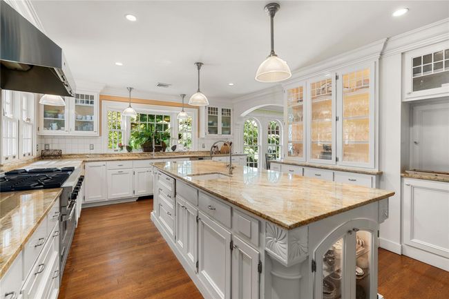 Kitchen featuring extractor fan, a center island with sink, tasteful backsplash, dark wood-type flooring, and a sink | Image 7