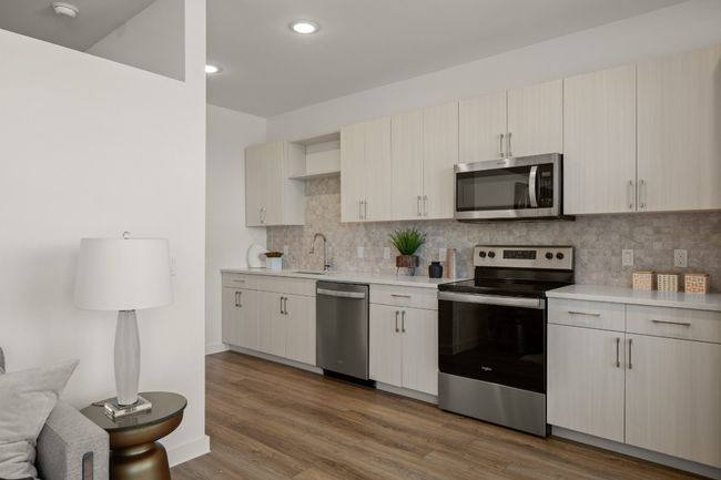 Kitchen featuring appliances with stainless steel finishes, wood finished floors, light countertops, and backsplash | Image 8