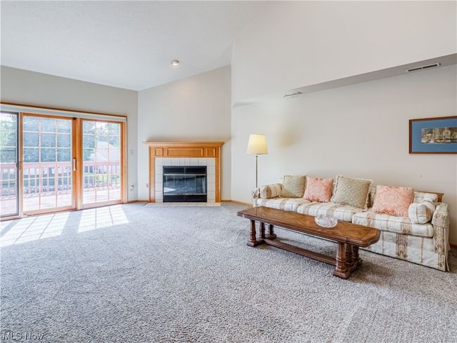 Carpeted living room featuring a fireplace, vaulted ceiling, and a high ceiling | Image 9