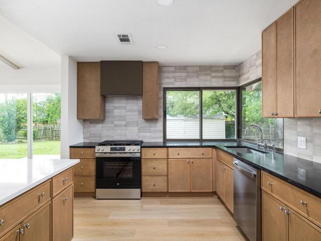 Kitchen featuring stainless steel appliances, light wood-style flooring, tasteful backsplash, recessed lighting, and wall chimney exhaust hood | Image 14