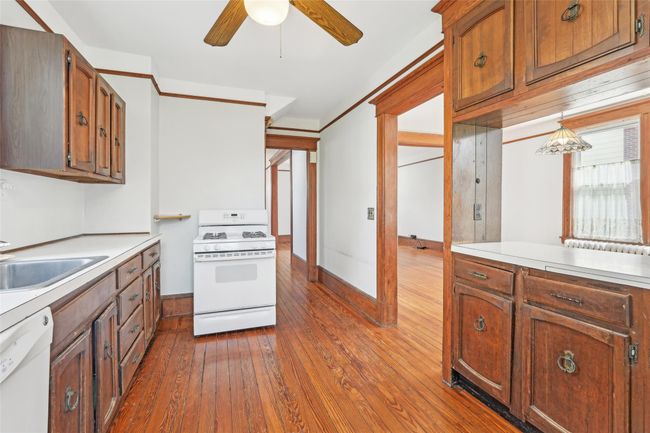 Kitchen with white appliances, a ceiling fan, hardwood / wood-style floors, light countertops, and a sink | Image 13