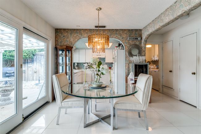 Dining area featuring a textured ceiling, light tile patterned floors, a chandelier, and arched walkways | Image 10