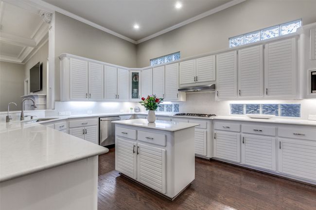 The kitchen has been updated with white stone countertops and high-end appliances, and it has contemporary styled cabinetry and glass-blocked transom windows for extra light. | Image 14
