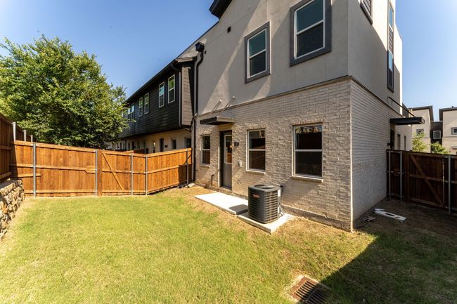 Rear view of house featuring central AC, a fenced backyard, stucco siding, a lawn, and brick siding | Image 13