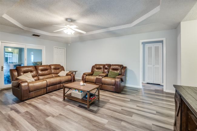 Living room featuring a raised ceiling, a textured ceiling, a ceiling fan, and light wood finished floors | Image 5