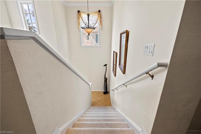 Staircase featuring a textured wall, tile patterned floors, and ornamental molding | Image 5