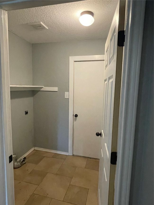 Washroom featuring light tile patterned floors, electric dryer hookup, and a textured ceiling | Image 7