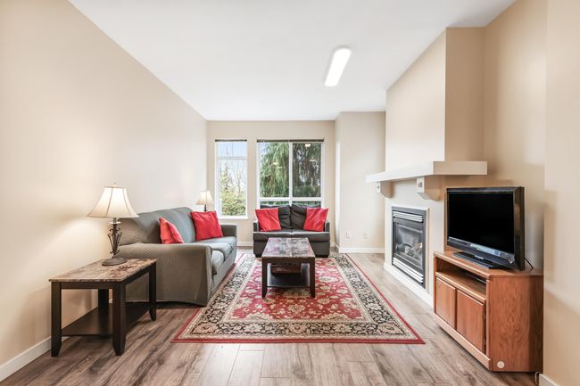 Living area with light wood-style flooring, a glass covered fireplace, and baseboards | Image 7