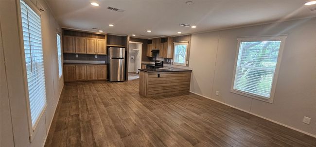 Kitchen featuring appliances with stainless steel finishes, dark countertops, dark wood-style floors, a peninsula, and recessed lighting | Image 14