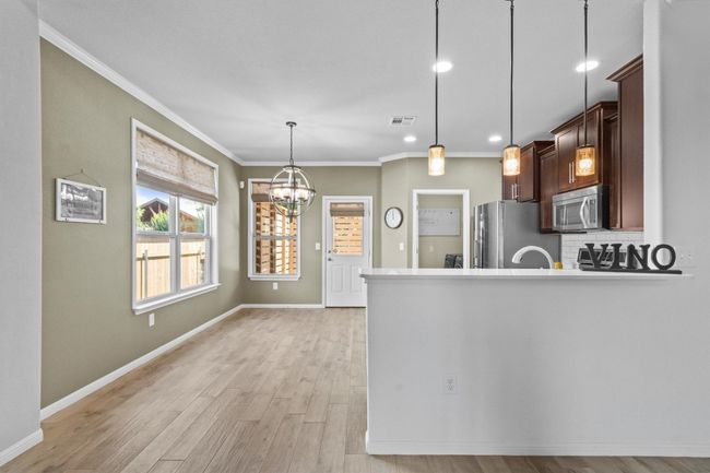 Kitchen with stainless steel appliances, ornamental molding, light wood-style floors, baseboards, and backsplash | Image 18