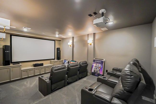 This home theater features a large screen, comfortable recliner seating, surround sound speakers, and subtle lighting, creating an ideal space for entertainment and movie nights. | Image 36