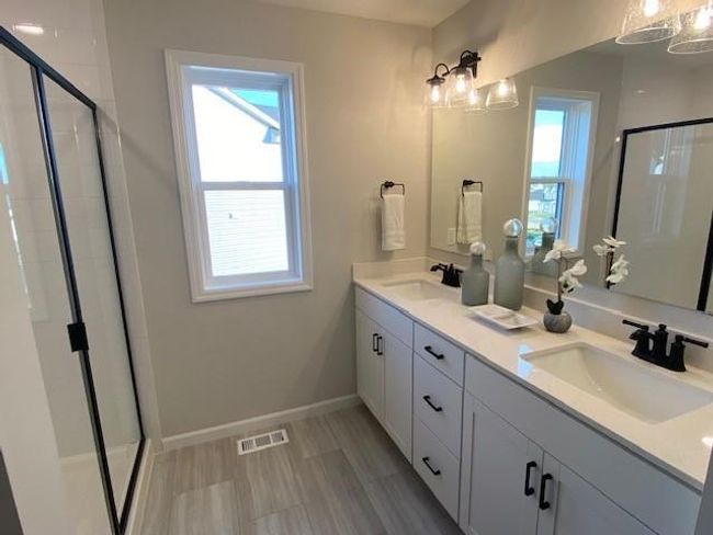 Spacious Owner's suite includes a lovely bathroom, with double sink, large tiled shower, toilet is tucked away, and large walk-in closet with shelving! | Image 16