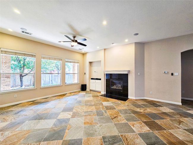 Unfurnished living room featuring stone tile flooring, ceiling fan, baseboards, a tiled fireplace, and recessed lighting | Image 8