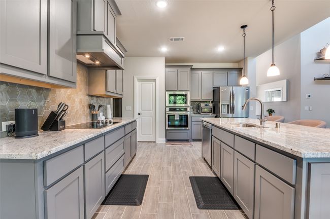 Kitchen with gray cabinetry, appliances with stainless steel finishes, backsplash, and recessed lighting | Image 13
