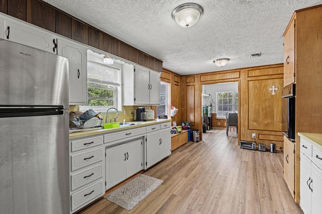 Kitchen featuring freestanding refrigerator, light countertops, light wood-style floors, a textured ceiling, and healthy amount of natural light | Image 20