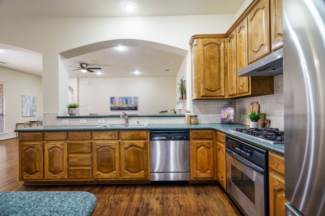 Kitchen featuring stainless steel appliances, a ceiling fan, arched walkways, under cabinet range hood, and a double sink | Image 5