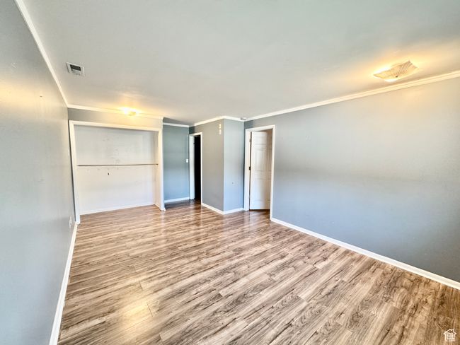 Interior space featuring visible vents, baseboards, crown molding, and wood finished floors | Image 29