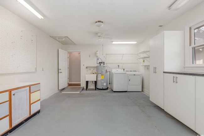Laundry area featuring washing machine and clothes dryer, attic access, electric water heater, baseboards, and a ceiling fan | Image 27