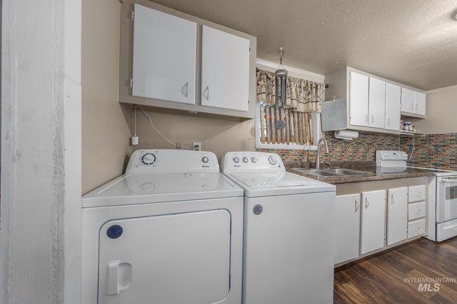 Washroom with separate washer and dryer, a textured ceiling, dark wood finished floors, and cabinet space | Image 12