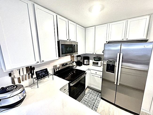 Kitchen featuring appliances with stainless steel finishes, white cabinets, and a textured ceiling | Image 5