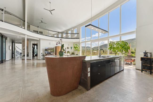 Kitchen featuring a sink, a kitchen island with sink, a towering ceiling, modern cabinets, and stainless steel dishwasher | Image 10