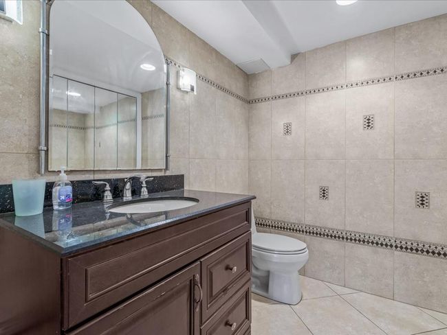 Bathroom featuring tile patterned floors, toilet, vanity, and tile walls | Image 22