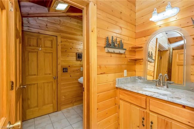 The lower level of the log cabin features a full bath conveniently located off the den, combining functionality with comfort in this rustic retreat. | Image 41