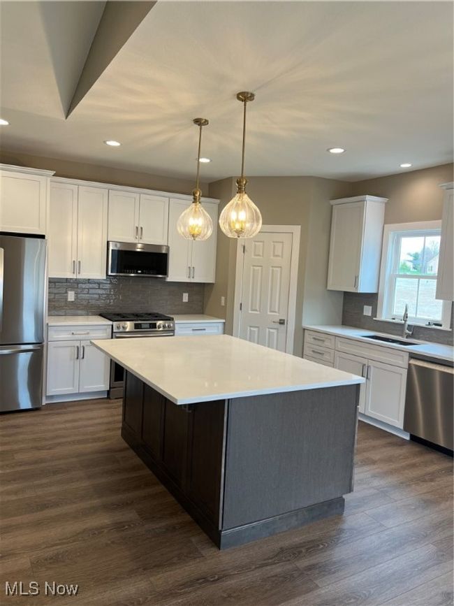 Kitchen featuring range, fridge, dishwashing machine, white cabinetry, and decorative backsplash | Image 18