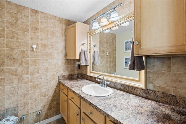 Bathroom with vanity, tasteful backsplash, tile walls, and a textured ceiling | Image 13