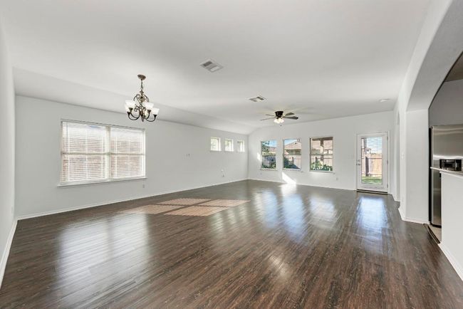 Unfurnished living room with a chandelier, ceiling fan, dark wood finished floors, and baseboards | Image 13