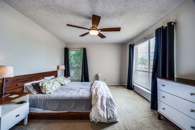 Carpeted bedroom with multiple windows, a textured ceiling, and a ceiling fan | Image 12