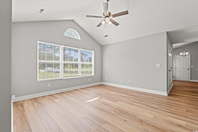 Unfurnished room featuring vaulted ceiling, a chandelier, a ceiling fan, and light wood-style floors | Image 8
