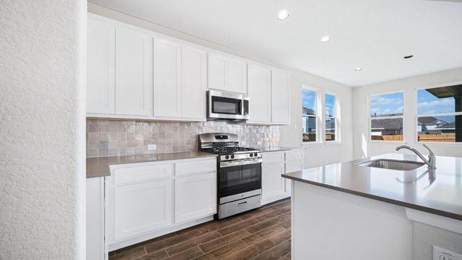 Kitchen with appliances with stainless steel finishes, recessed lighting, decorative backsplash, dark wood finished floors, and white cabinets | Image 13