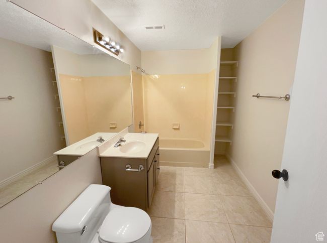 Full bathroom featuring tile patterned floors, a textured ceiling, visible vents, vanity, and tub / shower combination | Image 23
