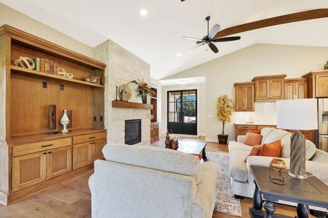 Living room featuring light wood-type flooring, vaulted ceiling, ceiling fan, and a stone fireplace | Image 8