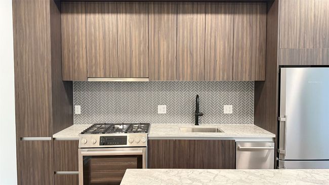 Kitchen with stainless steel appliances, modern cabinets, light countertops, and backsplash | Image 7