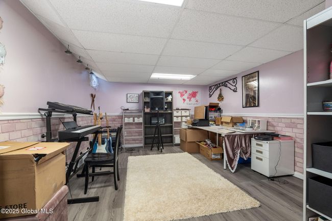 Basement finished area currently used as a craft room featuring gray LVP flooring, chair rail and large walk-in closet | Image 38