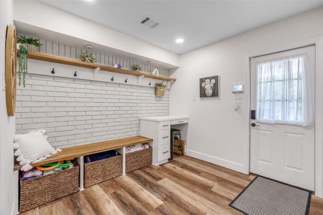 Step into a beautifully designed mud room showcasing a custom accent wall with convenient wall hooks and a built-in bench with storage underneath—combining style, function, and organization in one welcoming space. | Image 7