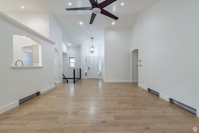 Unfurnished living room with high vaulted ceiling, light wood-type flooring, and ceiling fan | Image 3